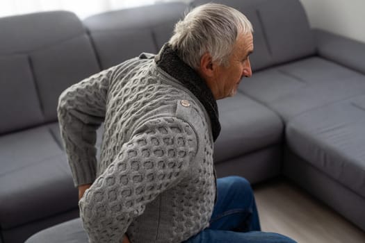 Elderly man near sofa with cactus at home. Hemorrhoids concept. High quality photo