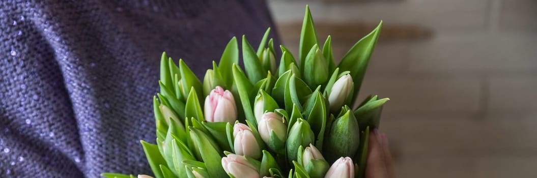 Very nice young woman standing outdoors, holding big and beautiful bunch of fresh red tulips, cropped photo, bouquet close up