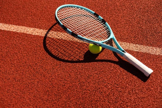 Balls and racket are lying on clay brown professional tennis court Close up of tennis balls and racket on dross at tennis court on the playground. Sport concept. Perspective up top view . High quality photo