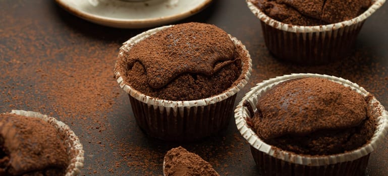 Chocolate and cocoa browny muffins with coffee cappuccino in cup angle view on brown rustic stone background, sweet homemade dark chocolate cupcakes.