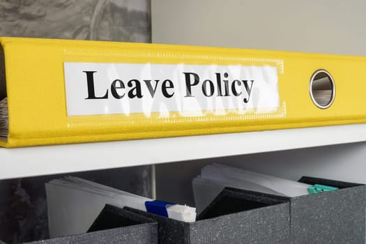 Folder Leave policy lies on the office shelf.