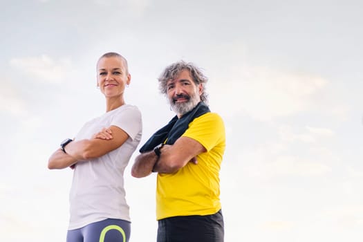 senior sportsman and young woman posing with arms crossed looking at camera, concept of active and healthy lifestyle in the middle age