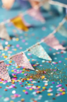 Vibrant birthday garland with multicolored flags and cascade of confetti on teal backdrop, softly blurred for festive atmosphere, ideal for celebration-themed designs or advertisements. Generative AI