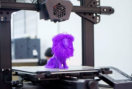 Model of toy lion printed on 3D printer from melted plastic purple color on desktop of 3D printer. Concept 3D printer, 3D printing, modeling prototyping three dimensional object. Innovative production