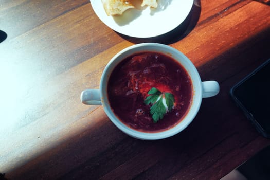 Russian borscht is poured into a plate and served in a cafe. High quality photo