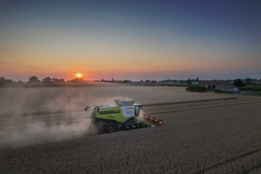 Soarza, Italy - June 23 2023 Claas 780 Lexion Combine Harvester threshing wheat in field at sunset