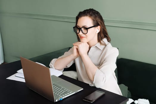 Connected and Smiling. Woman with Wireless Headphones Engages in Laptop Video Call, Watching and Talking. Happy Woman with Wireless Headphones Engages in Laptop Video Call.