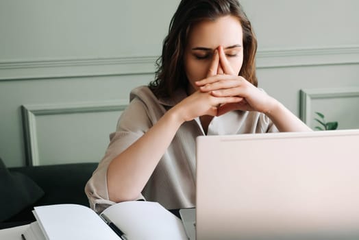 Stressed and Overworked Young Woman with Laptop, Battling Fatigue, Pressure, Migraine, and Stress. Modern Work Challenges. Sad Woman Suffering from Overwork. Tired and Unhappy