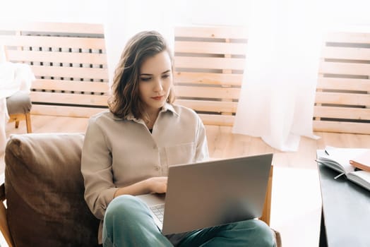 Modern Home Office. Woman Seriously Working on Laptop in Living Space. Efficient Remote Work. Woman Typing on Laptop in Living Room.