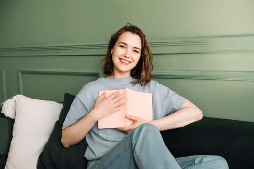 Joyful Middle-Aged Woman Holding a Book Close. Smiling Lady Embracing a Book with Cheerful Expression. Happiness and Literature Connection. Middle-Aged Woman Grasping a Book.