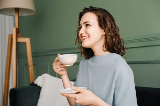 Relaxed Middle-Aged Woman Enjoying Tea on Couch, Gazing at Copy Space. Serene Moment of Contentment. Female Resting, Holding Cup, Space for Text or Advertising. Tranquil Leisure in Living Room.