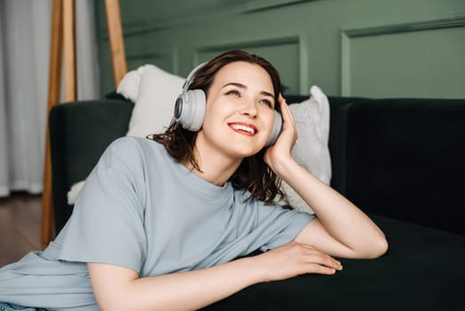 Weekend Vibes. Joyful Woman Relaxing on Sofa with Wireless Headphones, Enjoying Music. Relaxed Weekend. Happy Woman Enjoying Music on Couch with Wireless Headphones.