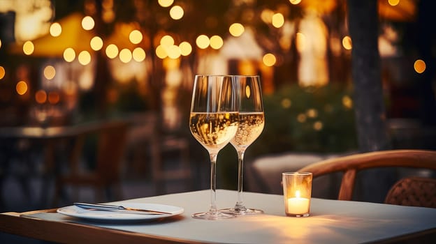 Dinner in a chic restaurant, on the terrace in the fresh air, by candlelight with a glass of champagne or wine, with beautiful glowing lights. Valentine's day, newlyweds, engagement, holiday, birthday, wedding, anniversary, surprise, date.