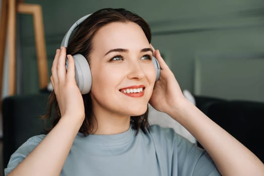 A smiling young middle-aged woman wearing wireless headphones listens to music. Musical Bliss. Middle-Aged Woman Embracing Joy Through Wireless Headphones. Rhythmic Escape.