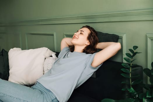 A cheerful young middle-aged woman with her eyes closed enjoying sleep on the living room couch. Blissful Slumber. Cheerful Middle-aged Woman Relaxes on Living Room Sofa.