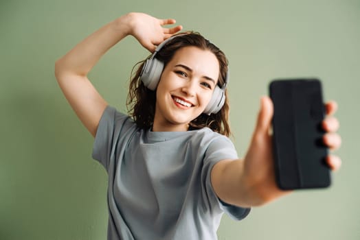 A young woman wearing wireless headphones listening to music, dancing. Energetic Beats. Young Lady Enjoys Music, Moves to the Rhythm. Dancing Melodies. Woman Grooving with Wireless Headphones.