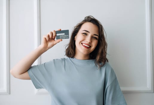 Positive Middle-Aged Woman Showing Credit Card in Close-up Studio Shot. Happy Middle-Aged Lady Presenting Credit Card, Studio Close-up. Middle-Aged Woman Grinning, Holding Credit Card.