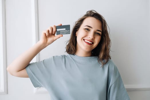 Smiling Middle-Aged Woman Displaying Credit Card in Studio Close-up. Cheerful Mature Woman Showing Credit Card in Studio, Close-up Shot. Joyful Middle-Aged Lady Displaying Credit Card with Smile.