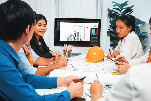 Diverse group of civil engineer and client working together on architectural project, reviewing construction plan and building blueprint at meeting table. Prudent