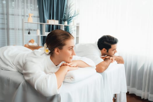 Caucasian couple customer enjoying relaxing anti-stress spa massage and pampering with beauty skin recreation leisure in day light ambient salon spa at luxury resort or hotel. Quiescent