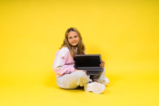 Teenager girl with notebok computer laptop sitting in a studio