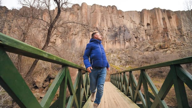 Happy tourist runs on a bridge over a river in the Ihlara Valley in Cappadocia, Turkey