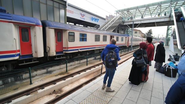 Ankara railway station with passengers and a passing train.