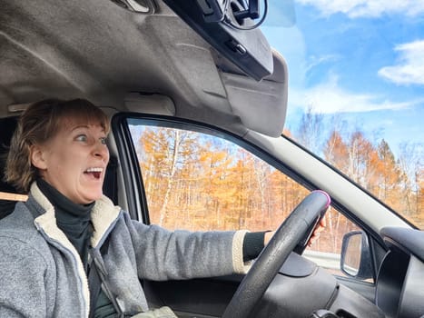 Terrified female driver a second before the accident. Scared middle-aged adult woman holds the steering wheel of car. Frightened Lady girl who is owner or rent a car for travel