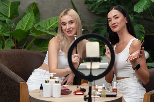 Two beautiful content creator making natural beauty and cosmetic tutorial on green plant garden video. Beauty blogger use camera light ring to show how to beauty care to social medial audience. Blithe