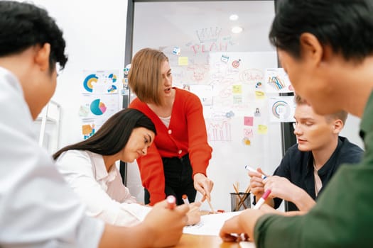 Happy cooperative multi-ethnic business group brainstorming discussion about marketing plan by using mind map in front of glass board with colorful sticky notes at meeting room. Immaculate.