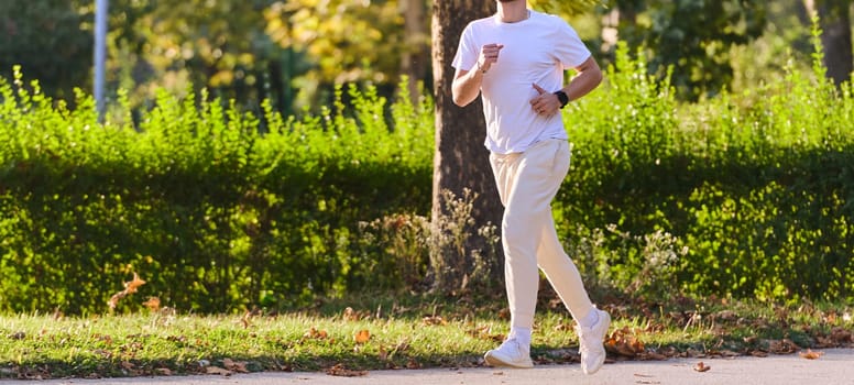 A handsome man maintains his healthy lifestyle as he runs along beautiful natural trails, embodying the essence of fitness, wellness, and vitality in the midst of scenic outdoor surroundings