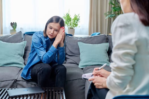 Sad young woman at therapy session with psychologist, psychiatrist. Therapist counselor and unhappy female patient on sofa in office. Psychology counseling treatment psychotherapy mental health youth