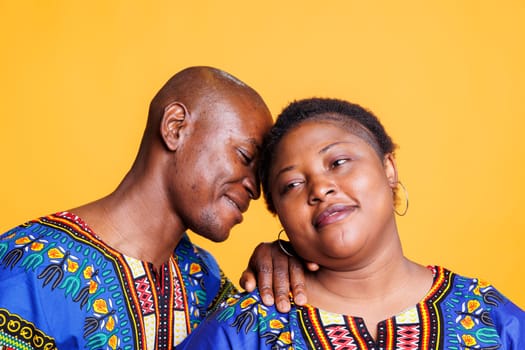 African american man and woman couple posing together, showing relationship bonding and love. Happy smiling husband leaning to wife with closed eyes, embracing and enjoying romance