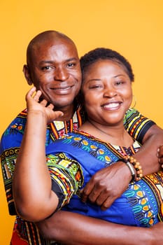 Smiling black couple in relationship embracing, showing love and happiness portrait. Joyful mature wife and husband romantic pair hugging and looking at camera with cheerful expression