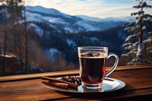 A glass of hot mulled wine with spices on a table overlooking the mountains.