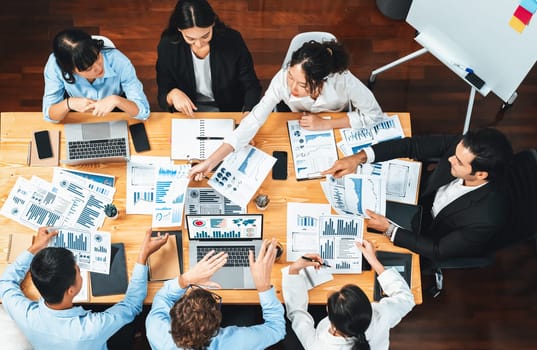 Panorama top view diverse group of business analyst team analyzing financial data report paper on meeting table. Chart and graph dashboard by business intelligence analysis. Meticulous