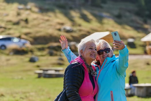 An elderly pair of women captures a timeless moment on their smartphones, blending technology with the serene beauty that surrounds them.