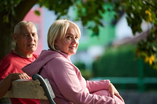 Elderly couple finding solace and joy as they rest on a park bench, engaged in heartfelt conversation, following a rejuvenating strol a testament to the enduring companionship and serene connection that accompanies the golden years.