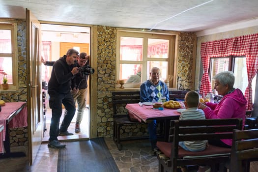 Videographers expertly capture the cinematic beauty of an elderly couple sharing a heartwarming breakfast with their grandchild at a rustic weekend retreat, preserving the cherished memories of generational love and togetherness.