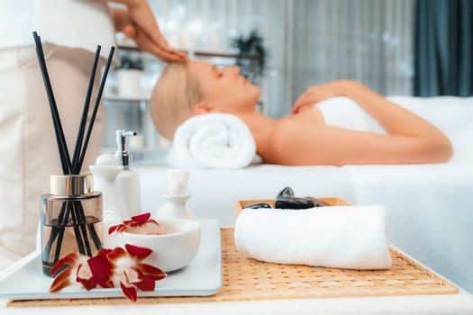 Aromatherapy massage on daylight ambiance or spa salon composition setup with focus decor and spa accessories on blur woman enjoying blissful aroma spa massage in resort or hotel background. Quiescent