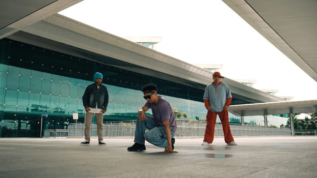 Group of diverse hipster or street dancer doing head spin in front of mall. Happy energetic break dancer practice b-boy step dancing with friends. Outdoor sport 2024. Street dancer concept. Sprightly.