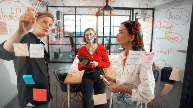 Creative start up team brainstorming marketing idea while cooperative caucasian businessman presents creative solution in front of glass board at business meeting. Working together. Immaculate.