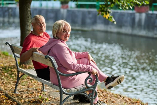 Elderly couple finding solace and joy as they rest on a park bench, engaged in heartfelt conversation, following a rejuvenating strol a testament to the enduring companionship and serene connection that accompanies the golden years.