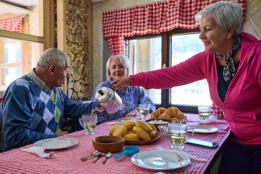 Elderly couple finds pure joy in the serene morning as they savor a cup of coffee, immersed in the tranquil beauty of nature that surrounds their rustic retreat.