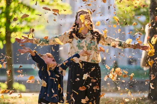 A modern woman joyfully plays with her son in the park, tossing leaves on a beautiful autumn day, capturing the essence of family life and the warmth of mother-son bonding in the midst of the fall season.