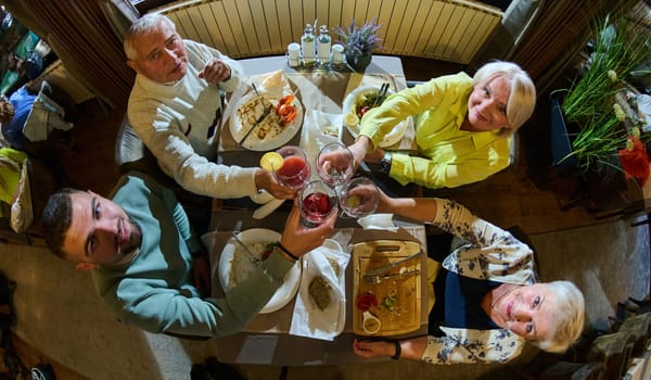 Top view photo of a modern multi generational family, including grandparents and a grandchild, raises a toast during a joyful dinner, epitomizing the warmth and unity shared across generations in their celebratory gathering.