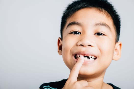 Six year old schoolboy happily points to growing molar gap beaming with joy in charming portrait. child dental care journey tooth exfoliation and joyous development. teeth new gap dentist problems