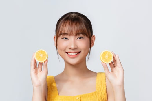 Portrait of beautiful young woman with fresh lemon near face over white background. 