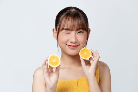 Organic cosmetics concept. A young girl with clean skin holds lemon slice near her face