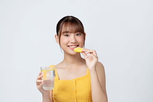young beautiful woman standing on a white wall, relaxing with a fresh water with lemon